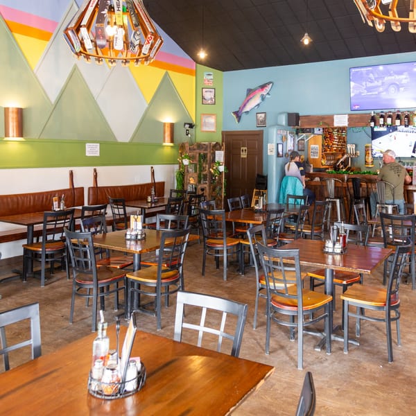 Angel Fired Pizza's dining room with tables, chairs, booths, and a bar area with patrons.