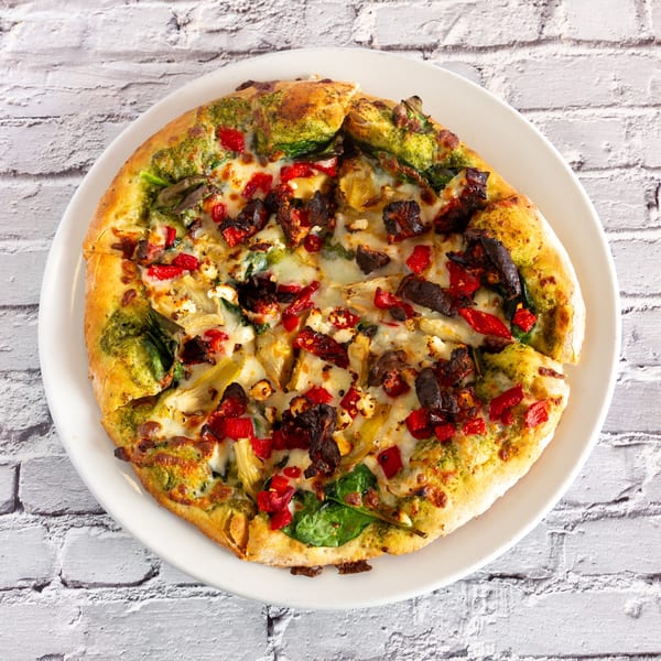 Angel Fired Pizza's pesto pizza with red peppers, artichoke hearts, spinach, and feta cheese.